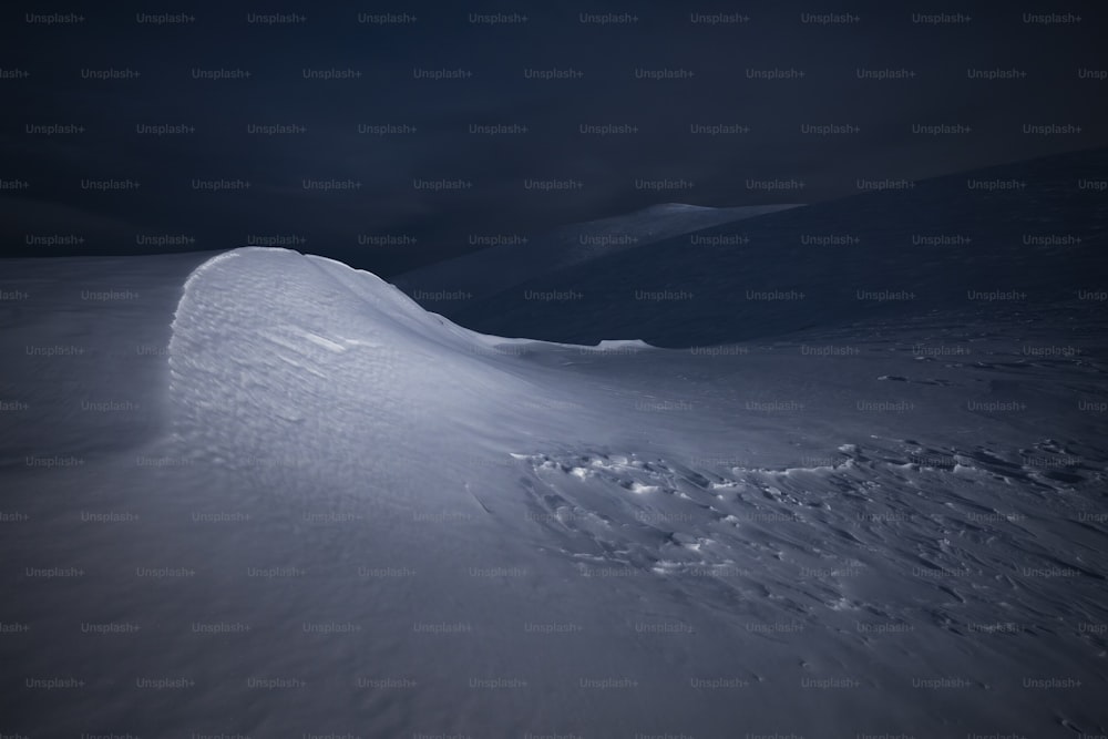 uma colina coberta de neve com um céu escuro no fundo
