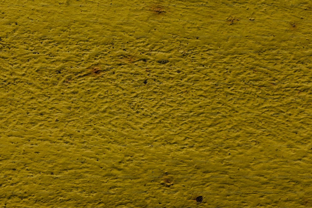 a close up of a yellow wall with some dirt on it