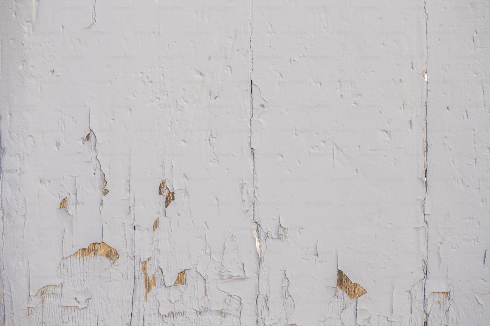 an old white painted wall with peeling paint