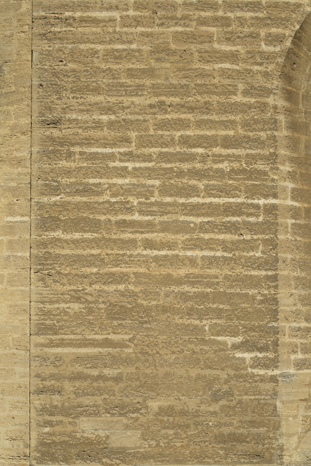 a man sitting on a bench in front of a brick wall