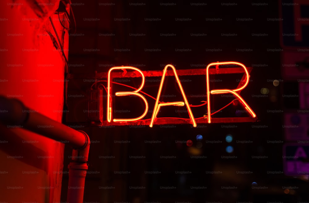 Une enseigne de bar au néon est illuminée dans l’obscurité