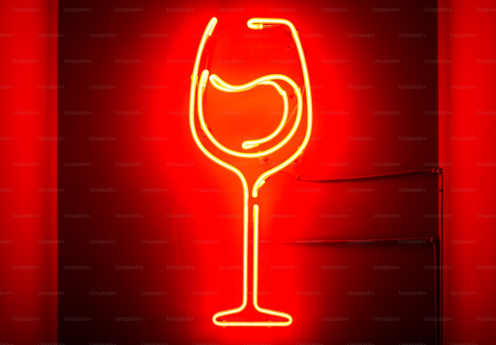 Un letrero de neón rojo con una copa de vino