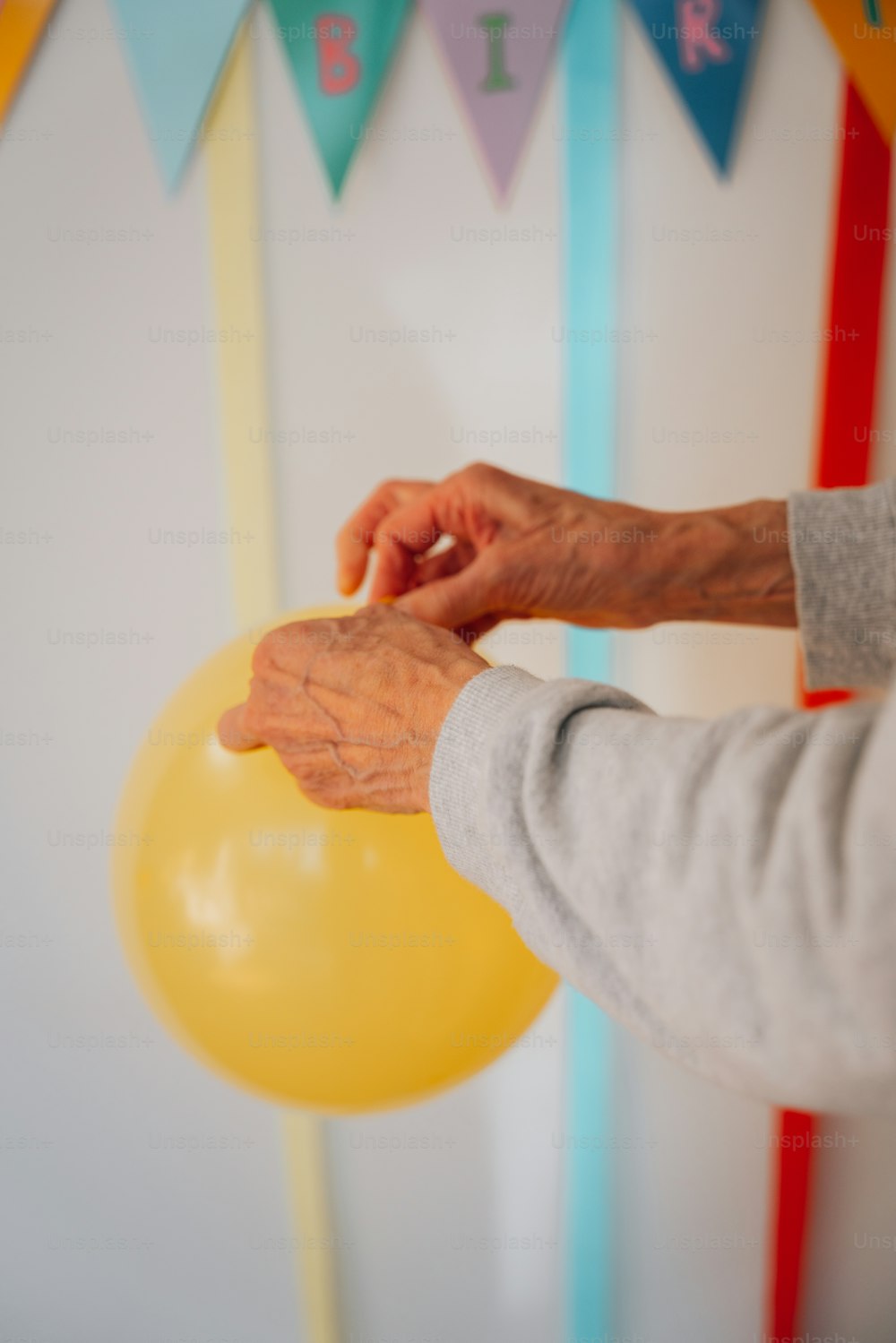 a person holding a yellow balloon in front of a wall