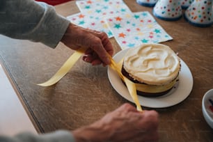 a person cutting a cake with a yellow ribbon