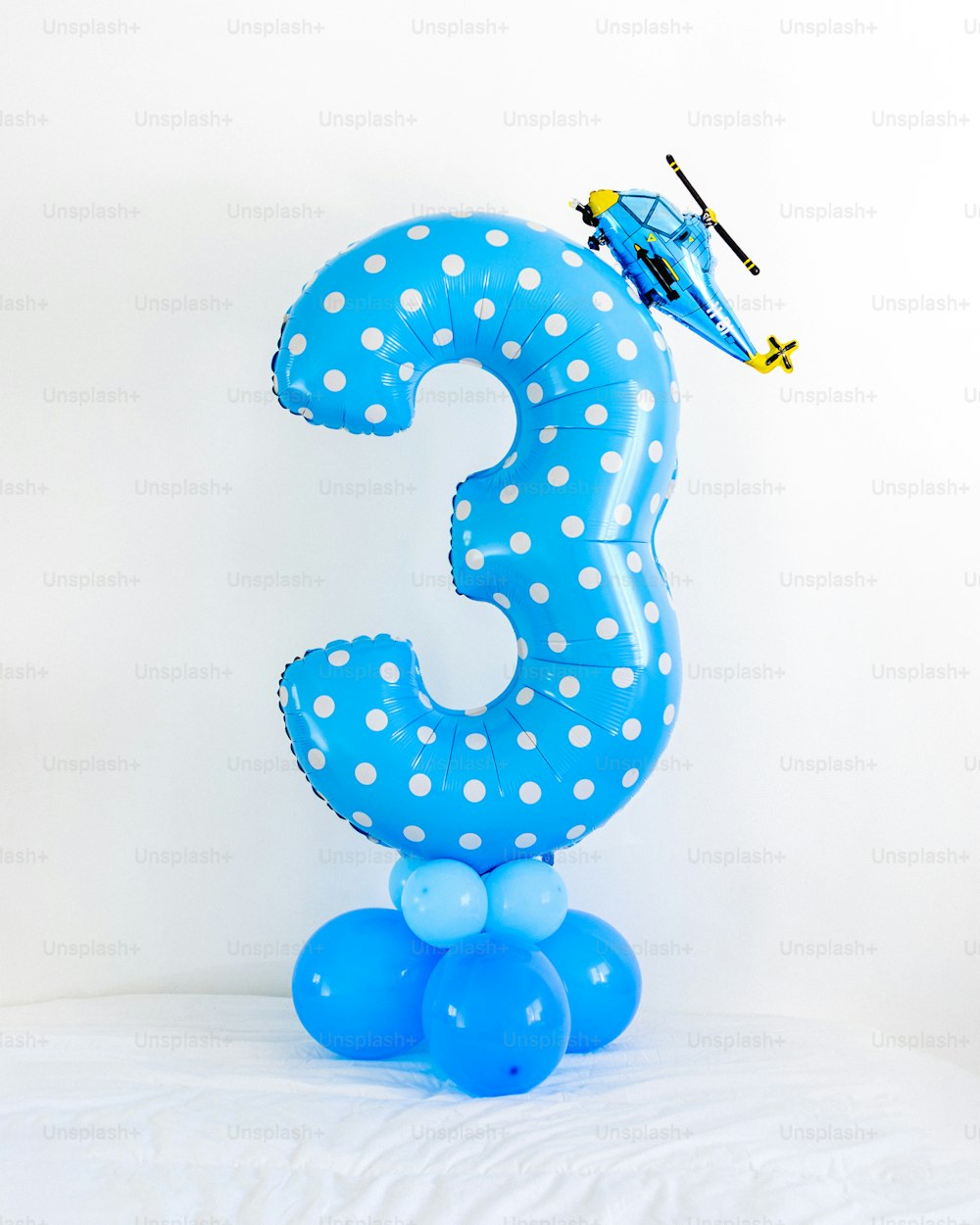 um balão número três azul com um helicóptero em cima dele