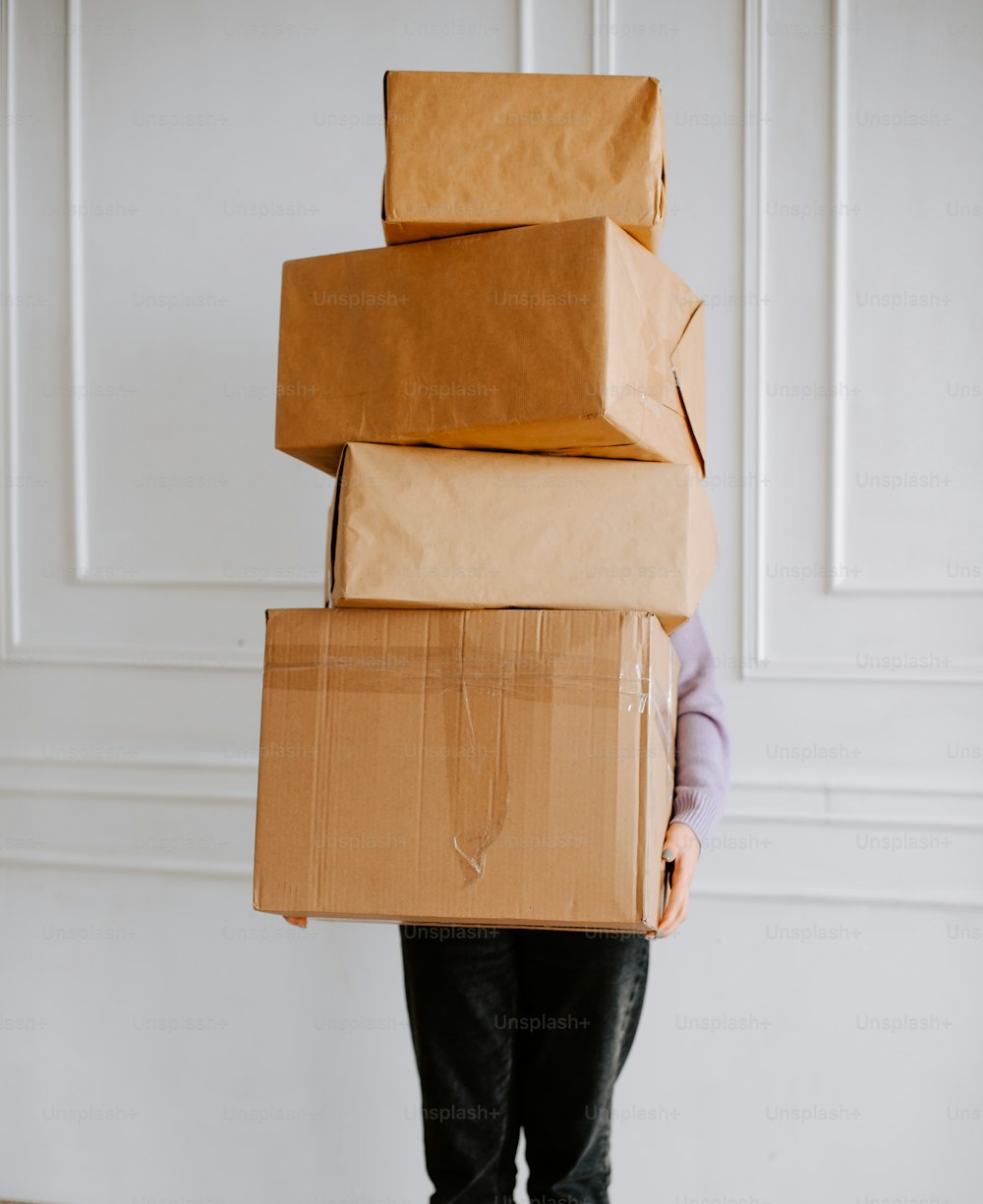 uma pessoa segurando uma pilha de caixas marrons