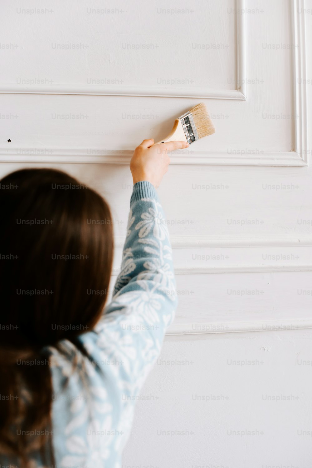 Eine Frau malt eine weiße Wand mit einem Pinsel