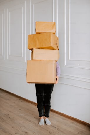 a woman holding a stack of boxes on her head