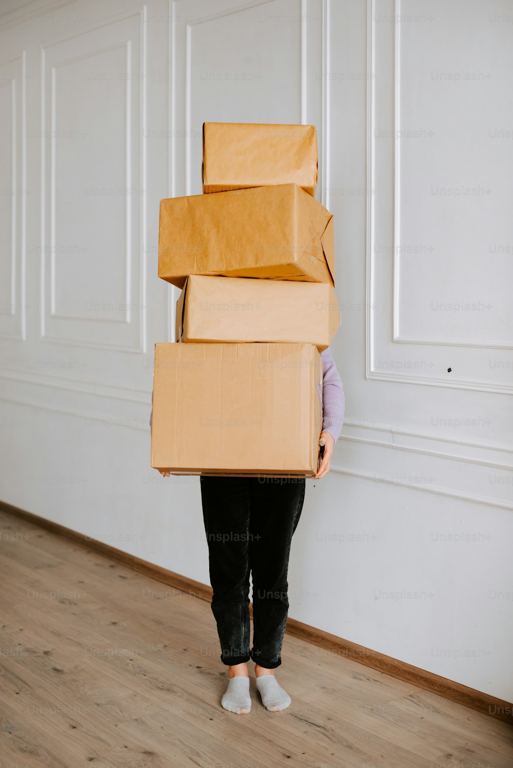 a woman holding a stack of boxes on her head