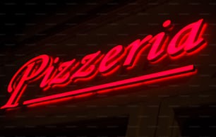 a red neon sign that says pizzeria on the side of a building