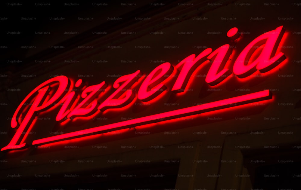 Eine rote Leuchtreklame mit der Aufschrift Pizzeria an der Seite eines Gebäudes