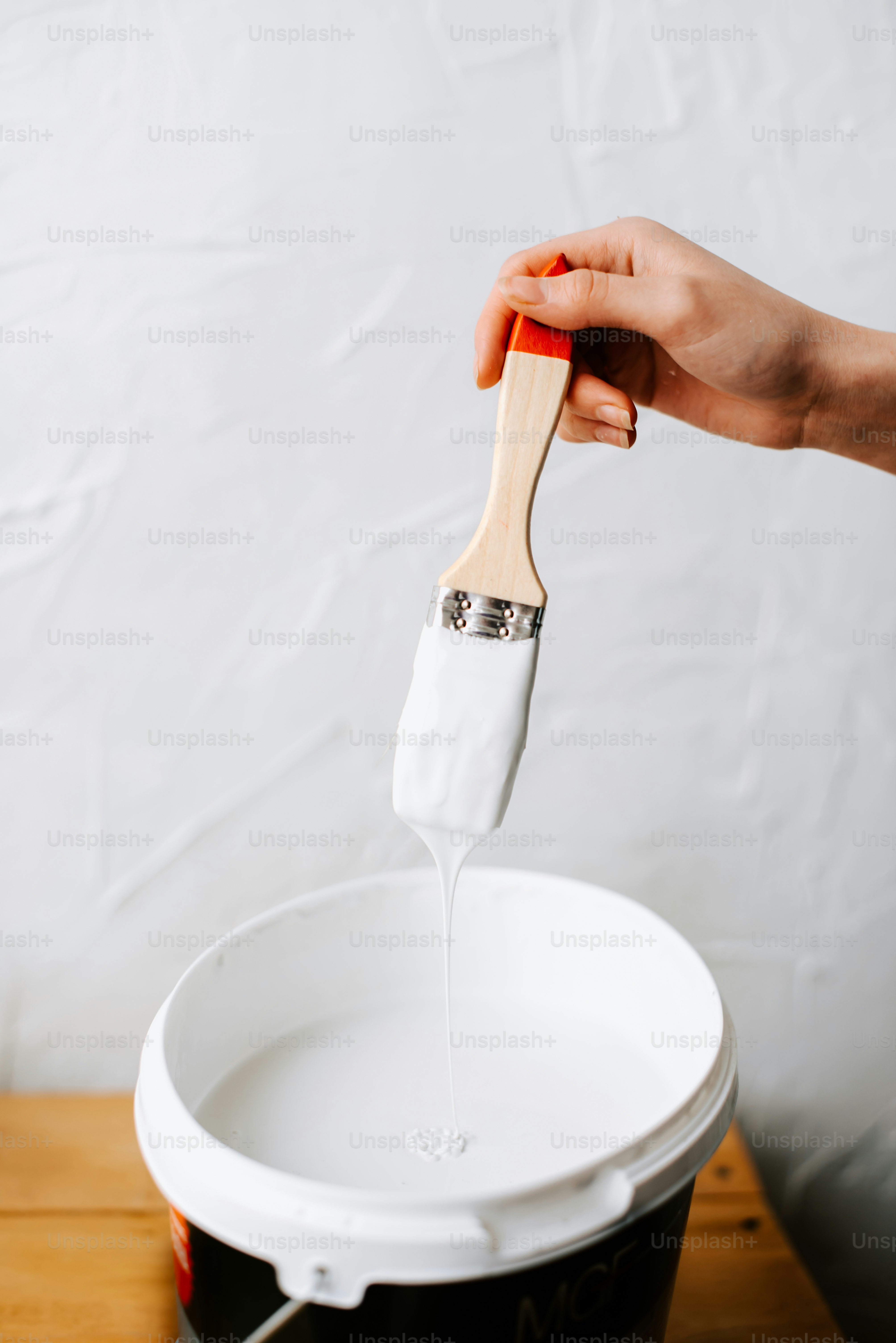 a person holding a wooden spatula over a white bucket
