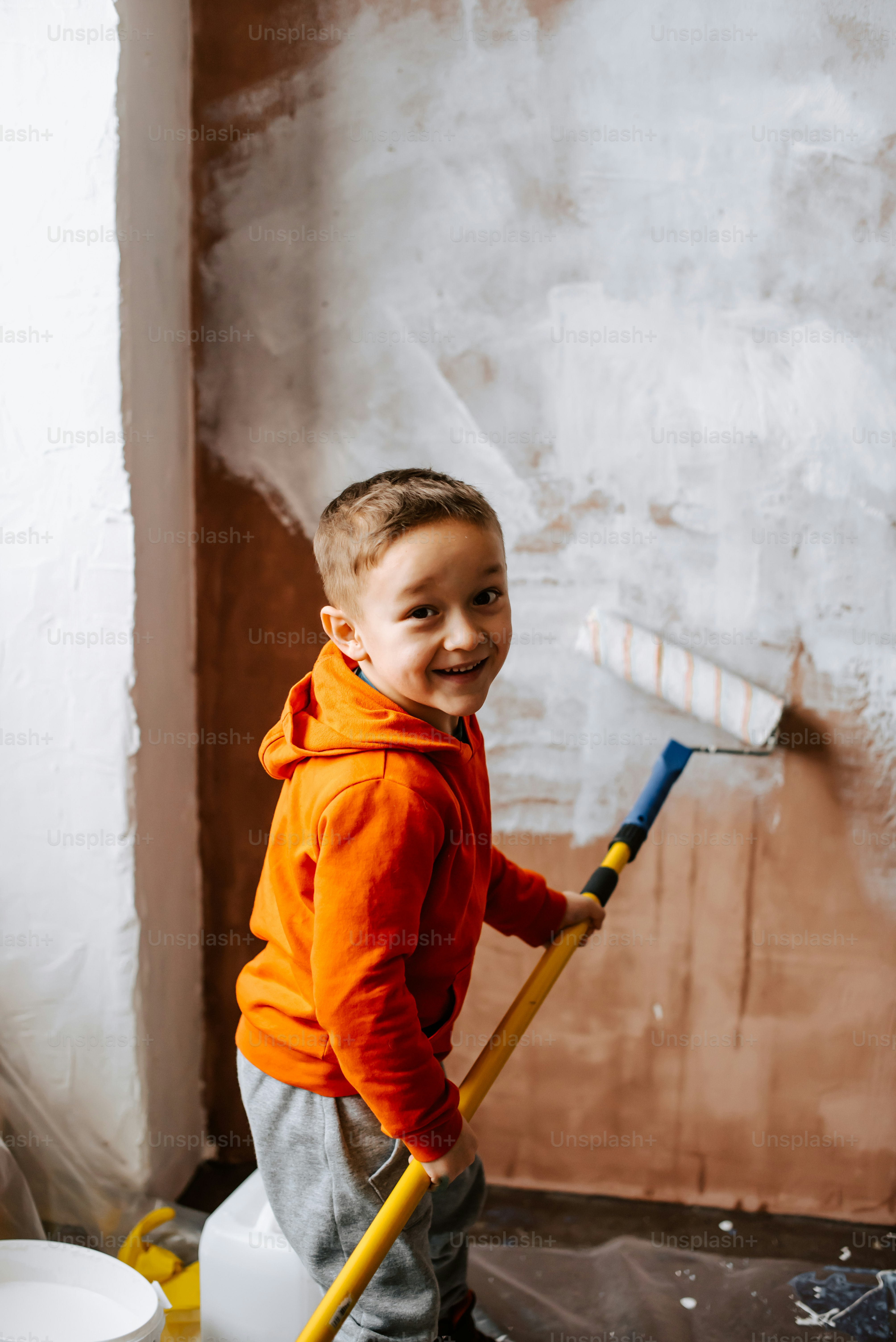 a young boy holding a broom in a room
