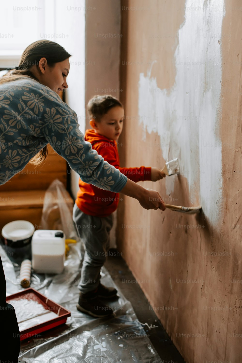 uma mulher e uma criança estão pintando uma parede