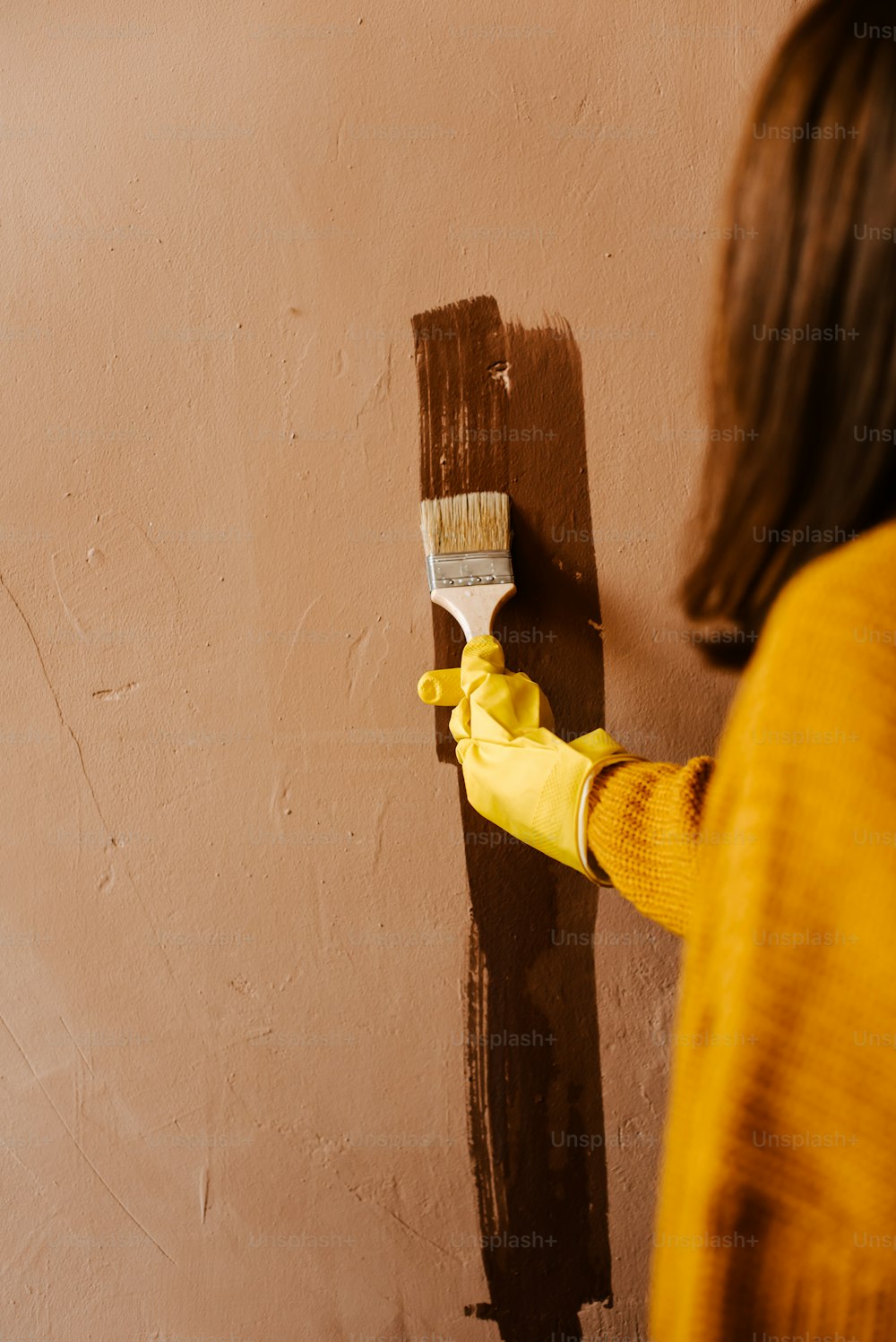 a woman painting a wall with a paint roller