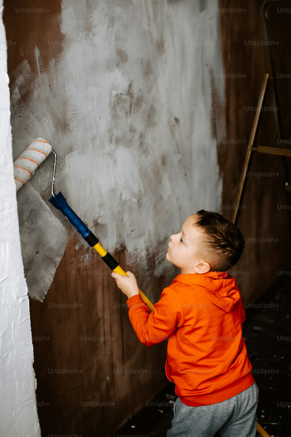 um menino pintando uma parede com um rolo de tinta