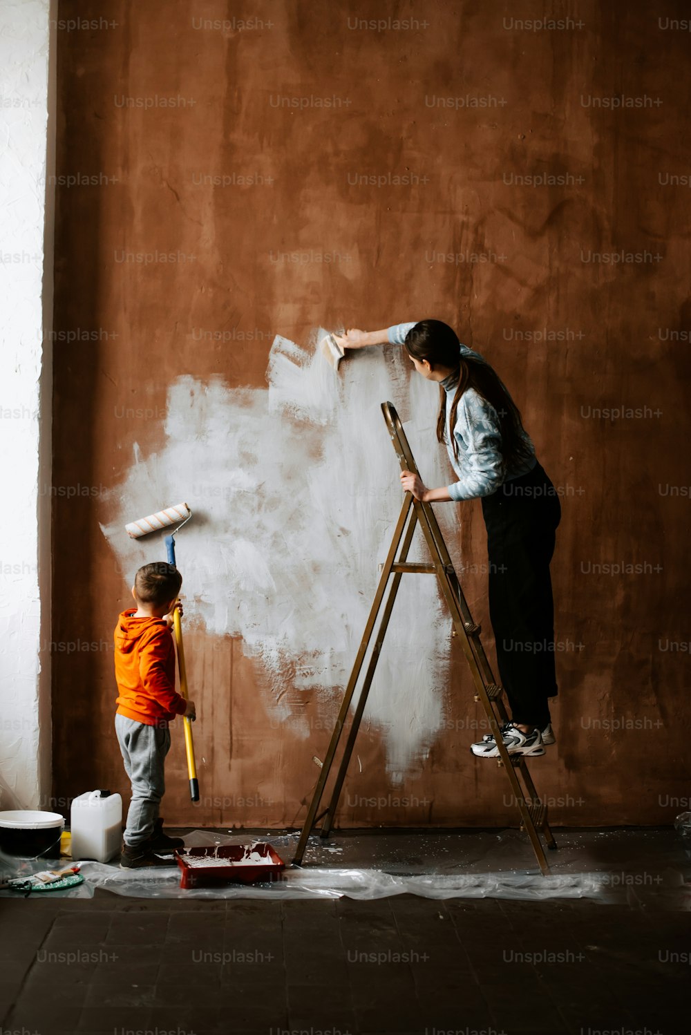 uma mulher e uma criança pintando uma parede