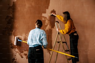 um homem e uma mulher pintando uma parede