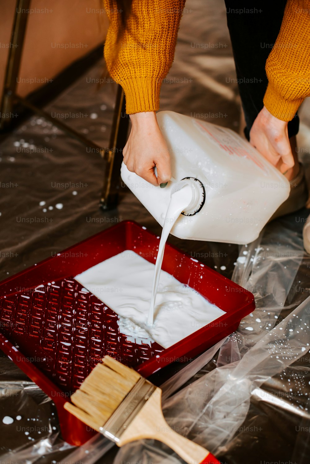 Eine Person, die Milch in einen roten Behälter gießt