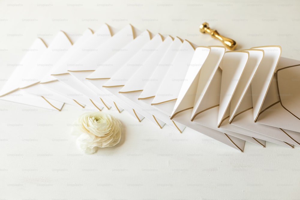 a white flower sitting next to a pile of folded paper