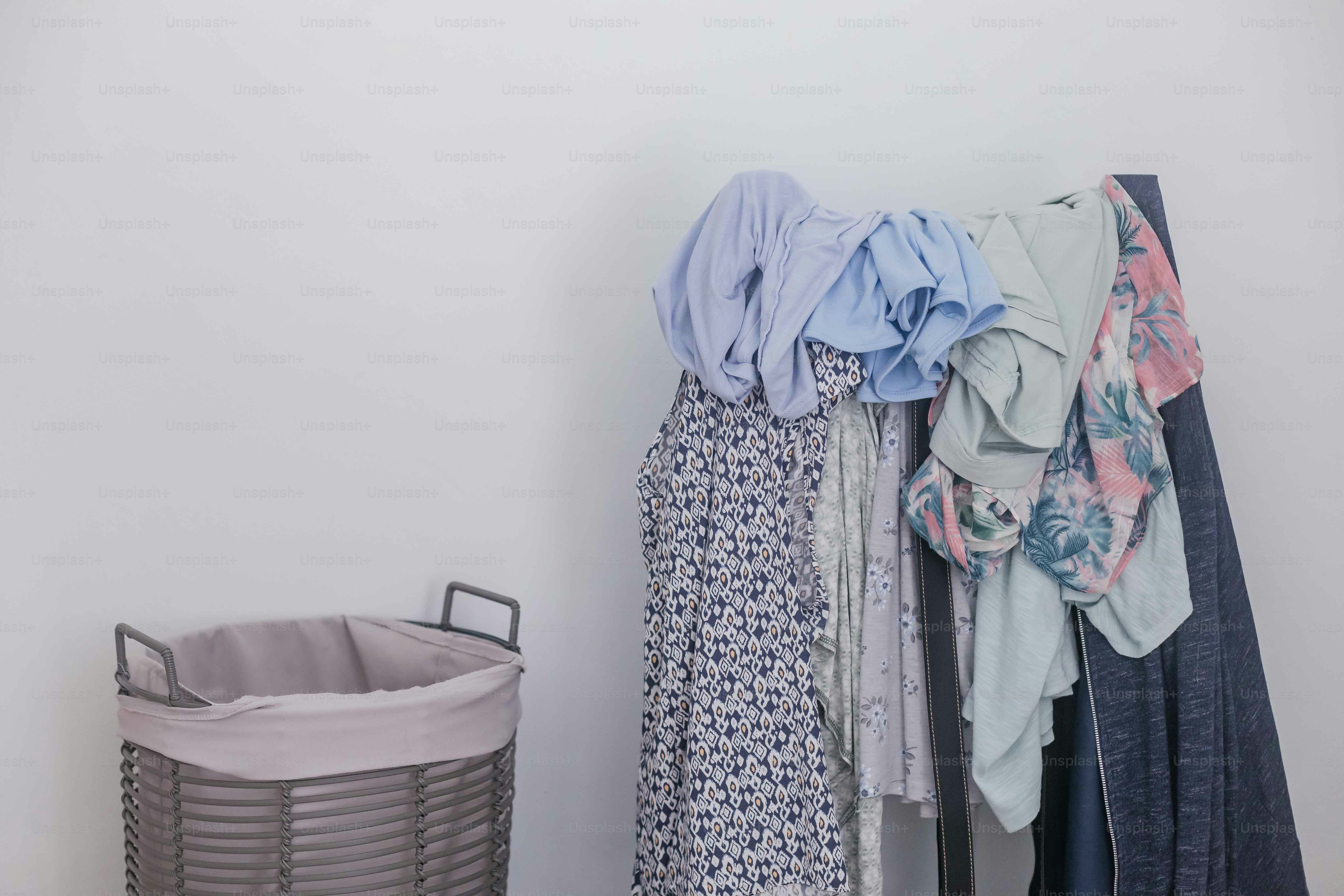 a closet with clothes and a basket on the floor