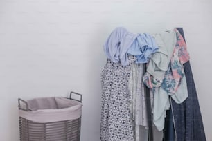 a closet with clothes and a basket on the floor