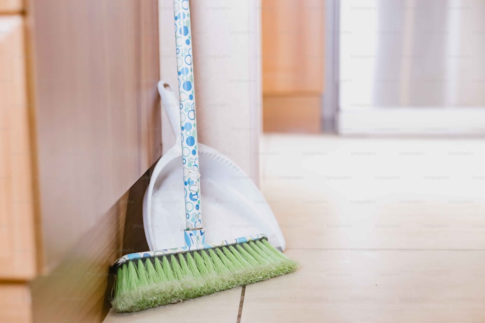 a broom leaning against a wall with a dustpan on it
