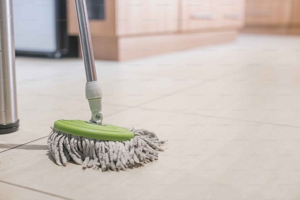 a mop on the floor with a green handle