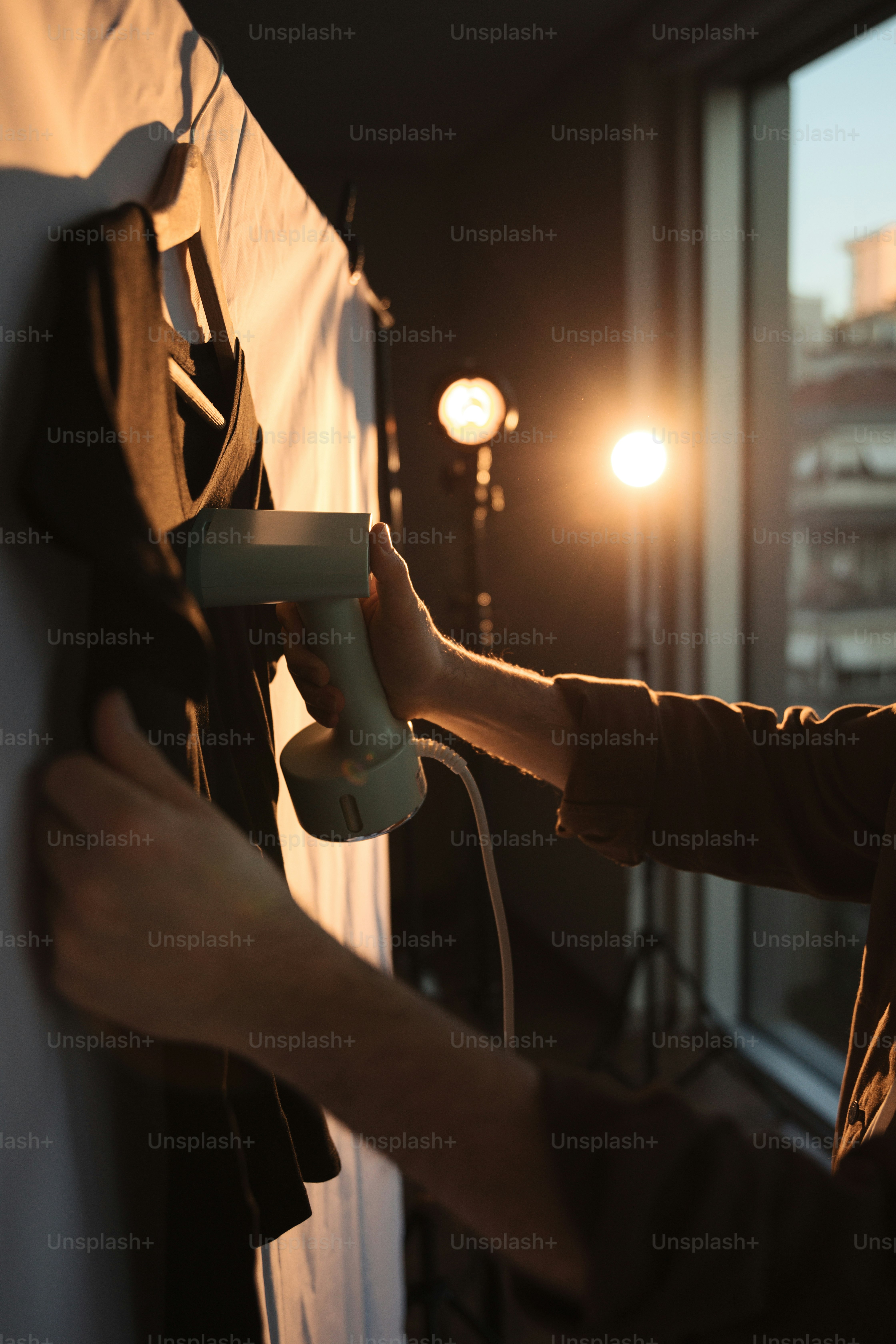 a man holding a hair dryer in front of a window