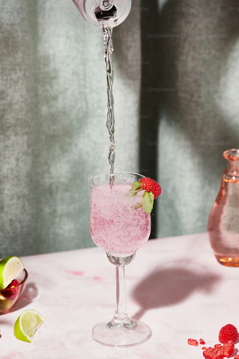 a pink drink being poured into a wine glass