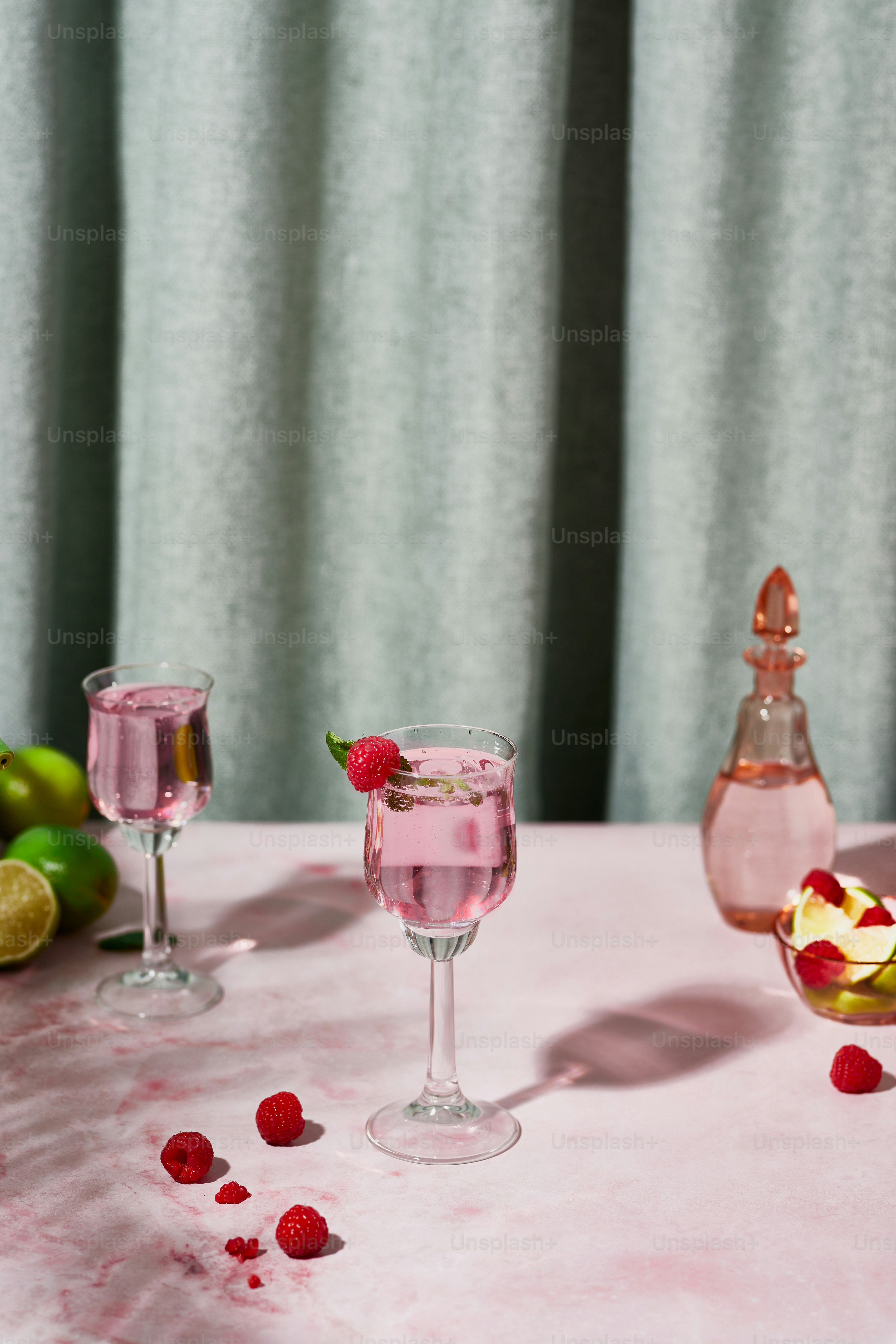 ein Tisch mit zwei Gläsern gefüllt mit Flüssigkeit und Himbeeren