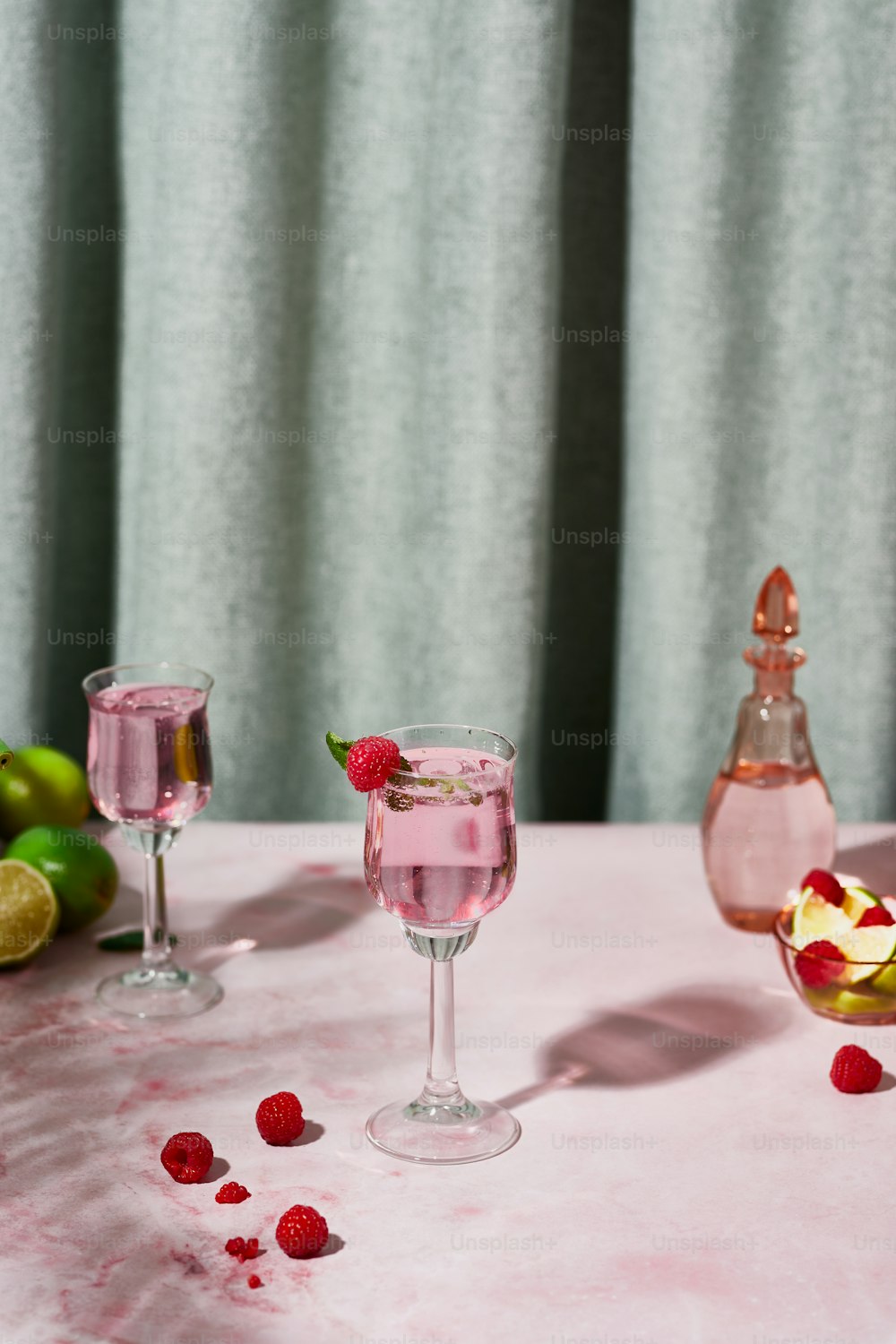 a table topped with two glasses filled with liquid and raspberries