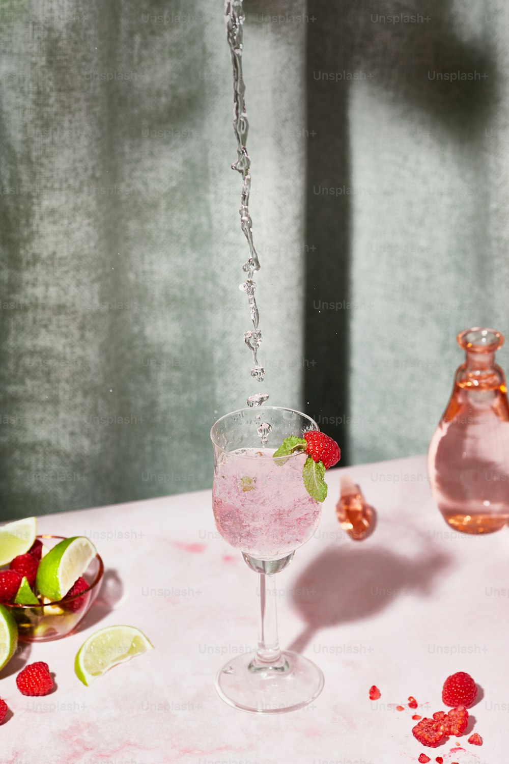 um copo de água com morangos e limas em uma mesa