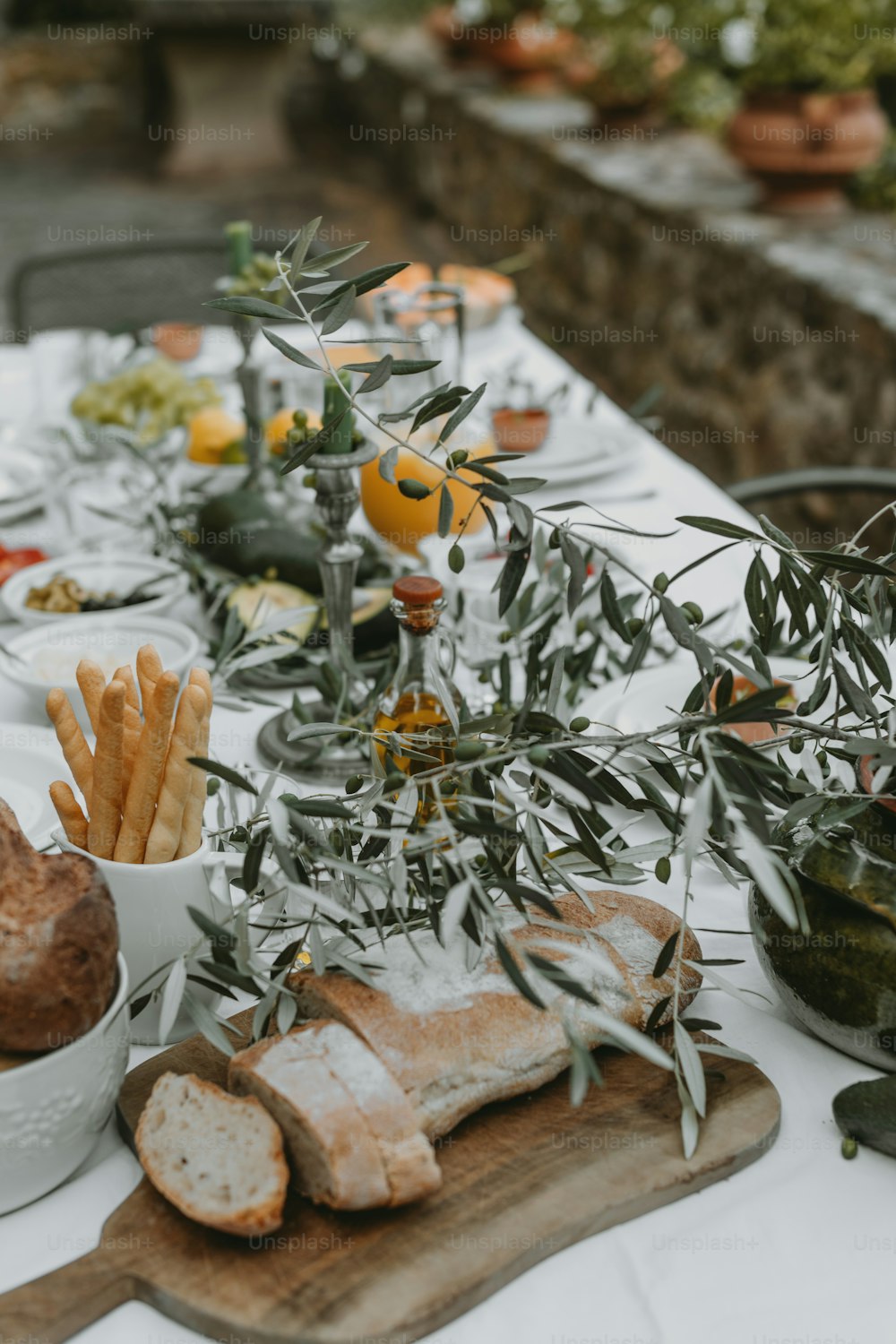 une table avec du pain, des gressins, des olives et des oranges