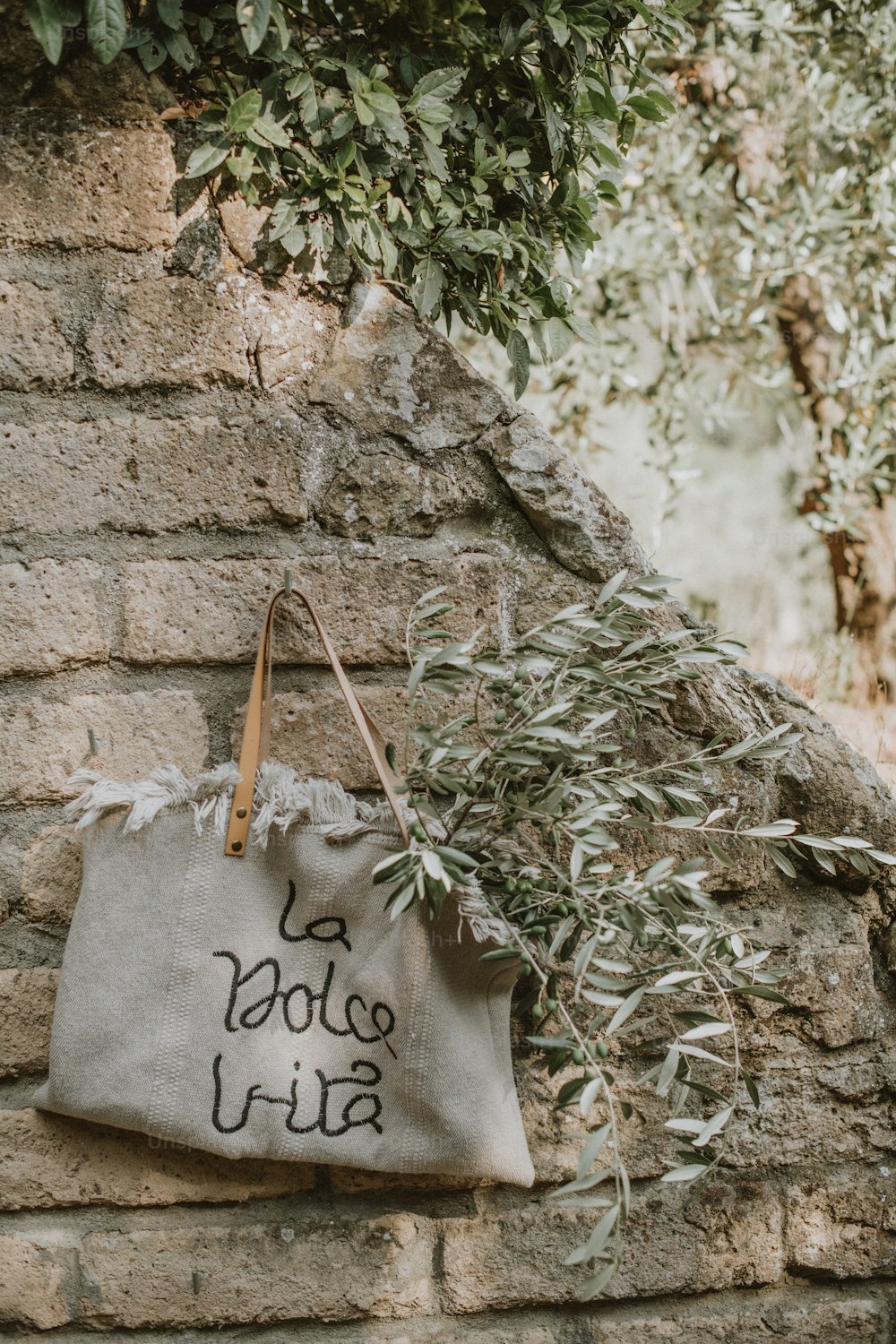 a bag with writing on it hanging on a brick wall