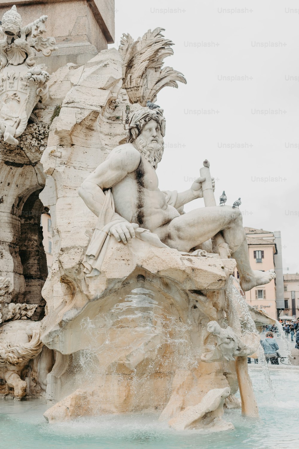 a statue of a man sitting on a rock next to a fountain