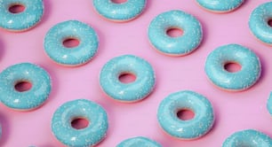 a group of blue donuts sitting on top of a pink surface