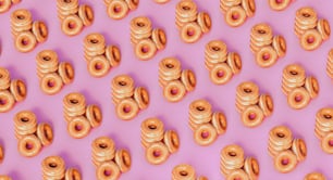 um monte de donuts que estão em uma superfície rosa