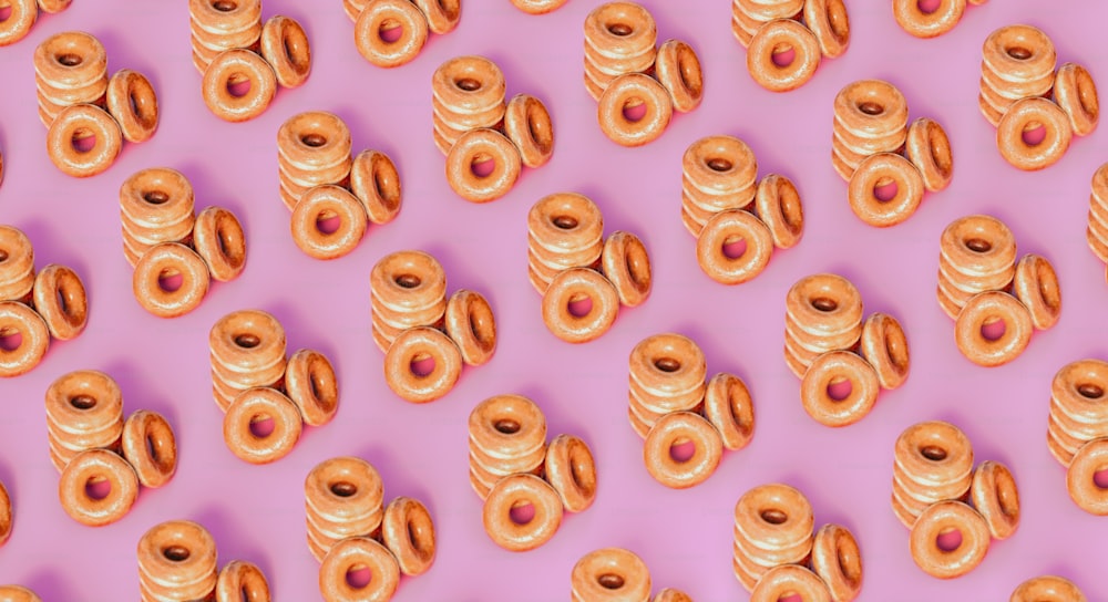 a lot of donuts that are on a pink surface
