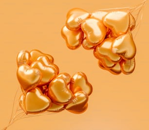 Un montón de globos dorados en forma de corazón flotando en el aire