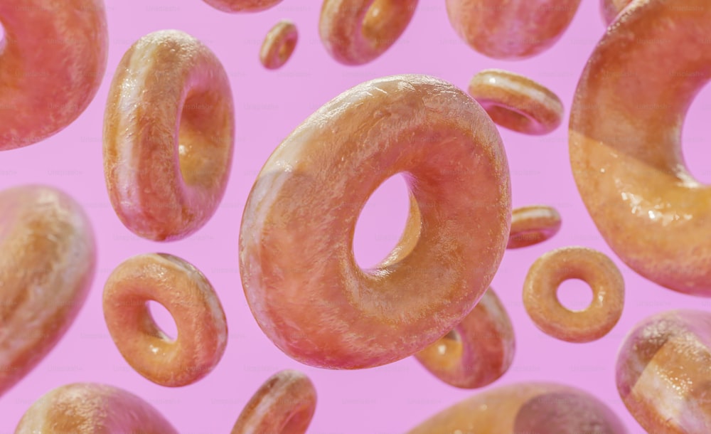 um monte de donuts que estão em uma superfície rosa