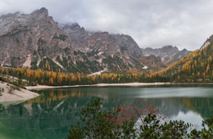 a lake surrounded by mountains with trees in the foreground