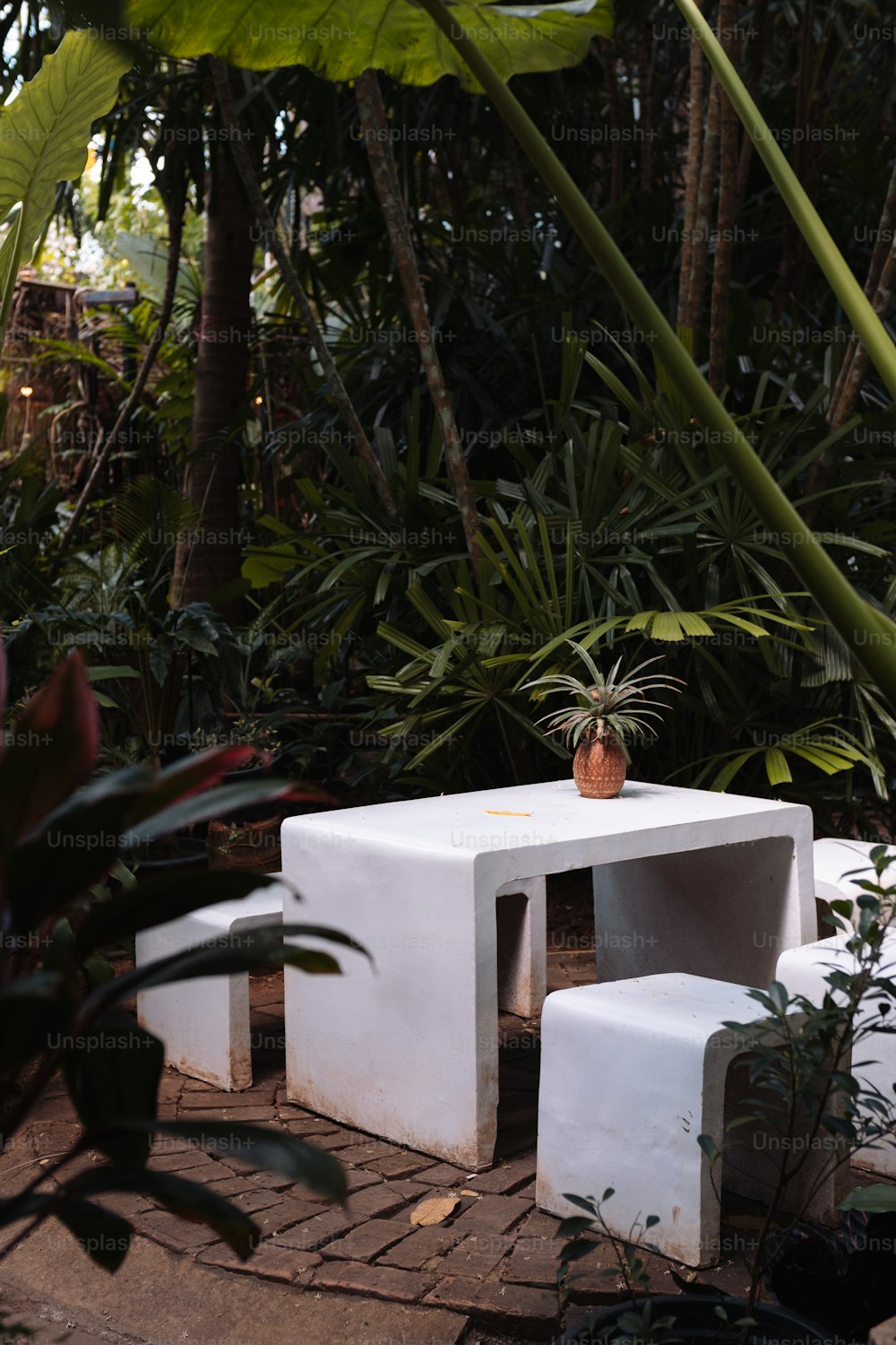 ein weißer Tisch und zwei weiße Hocker in einem Garten
