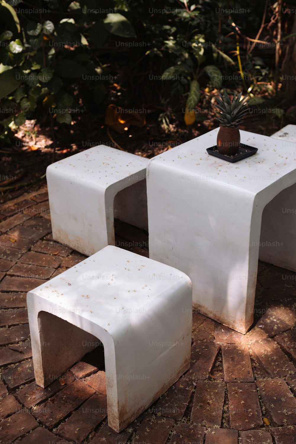 um par de mesas brancas sentadas em cima de um chão de tijolos