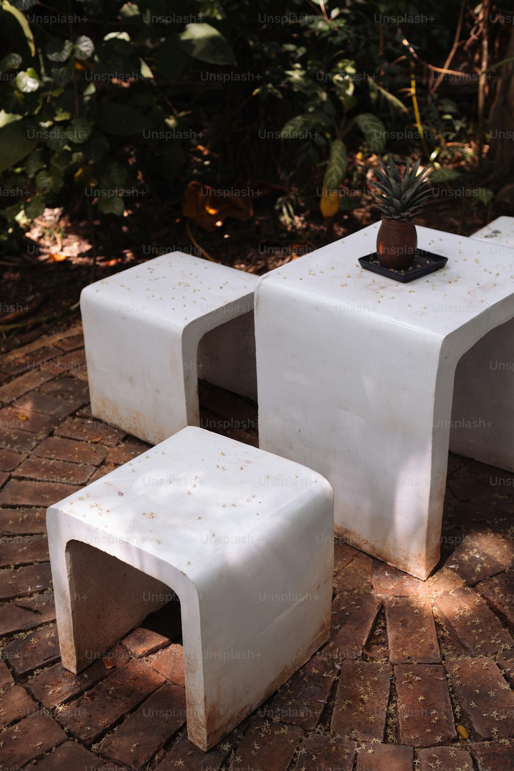 a couple of white tables sitting on top of a brick floor