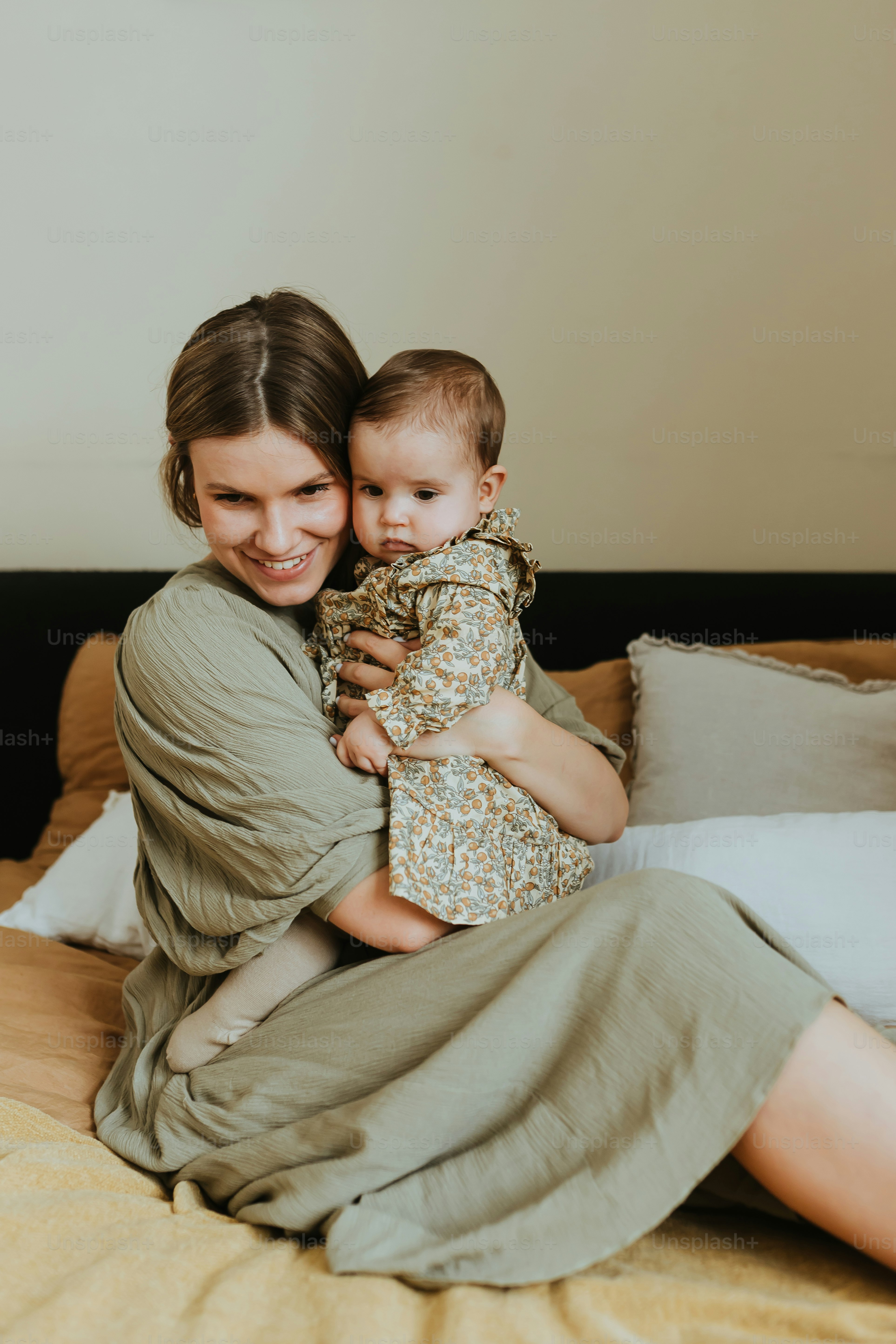 a woman sitting on a bed holding a baby