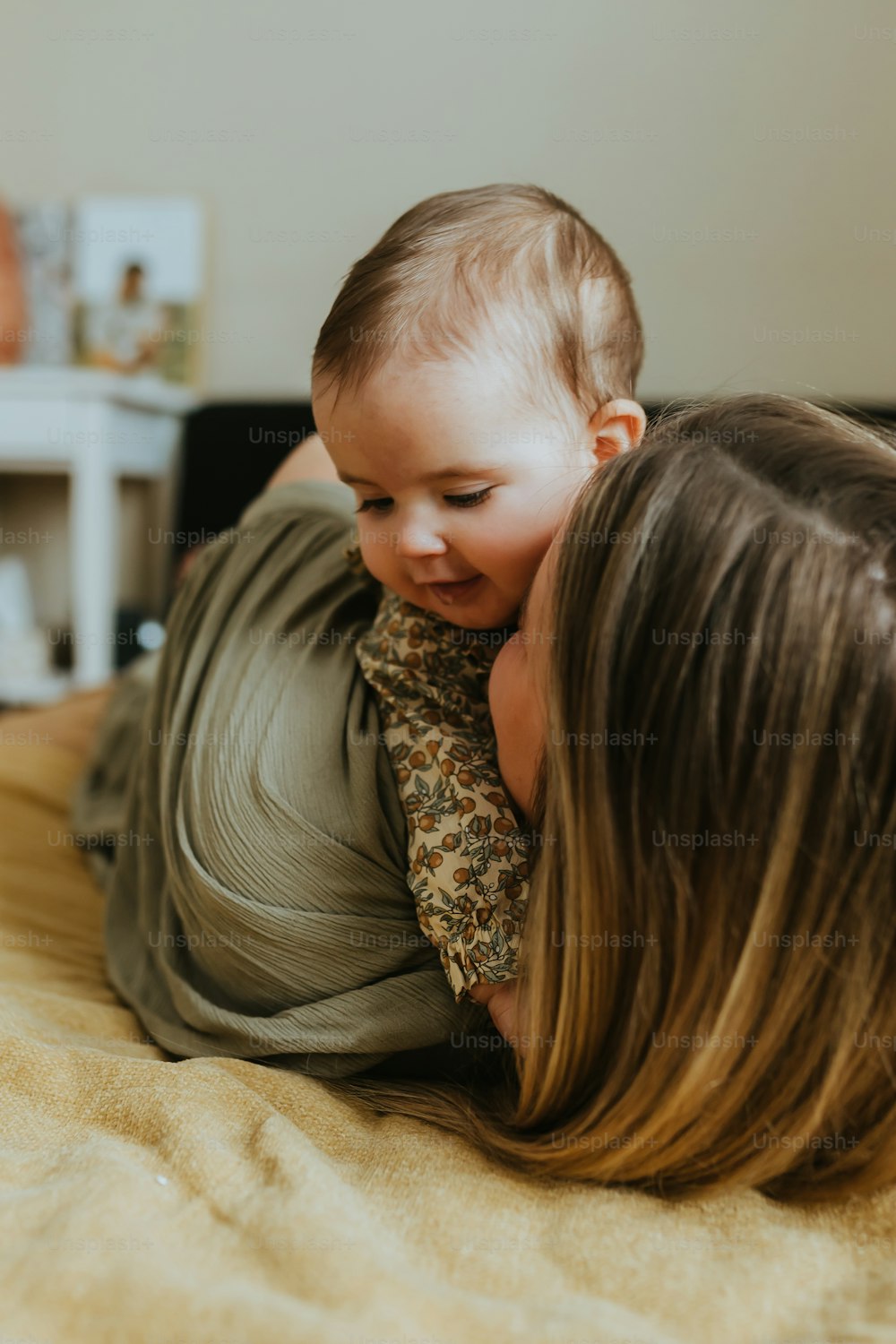 a woman laying on top of a bed holding a baby