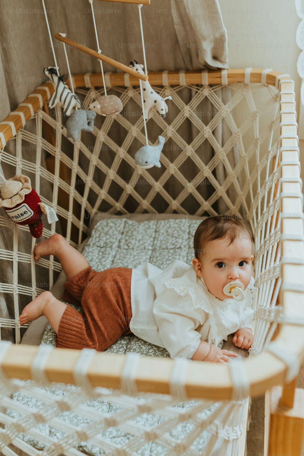 Un bebé acostado en una cuna con un chupete en la boca