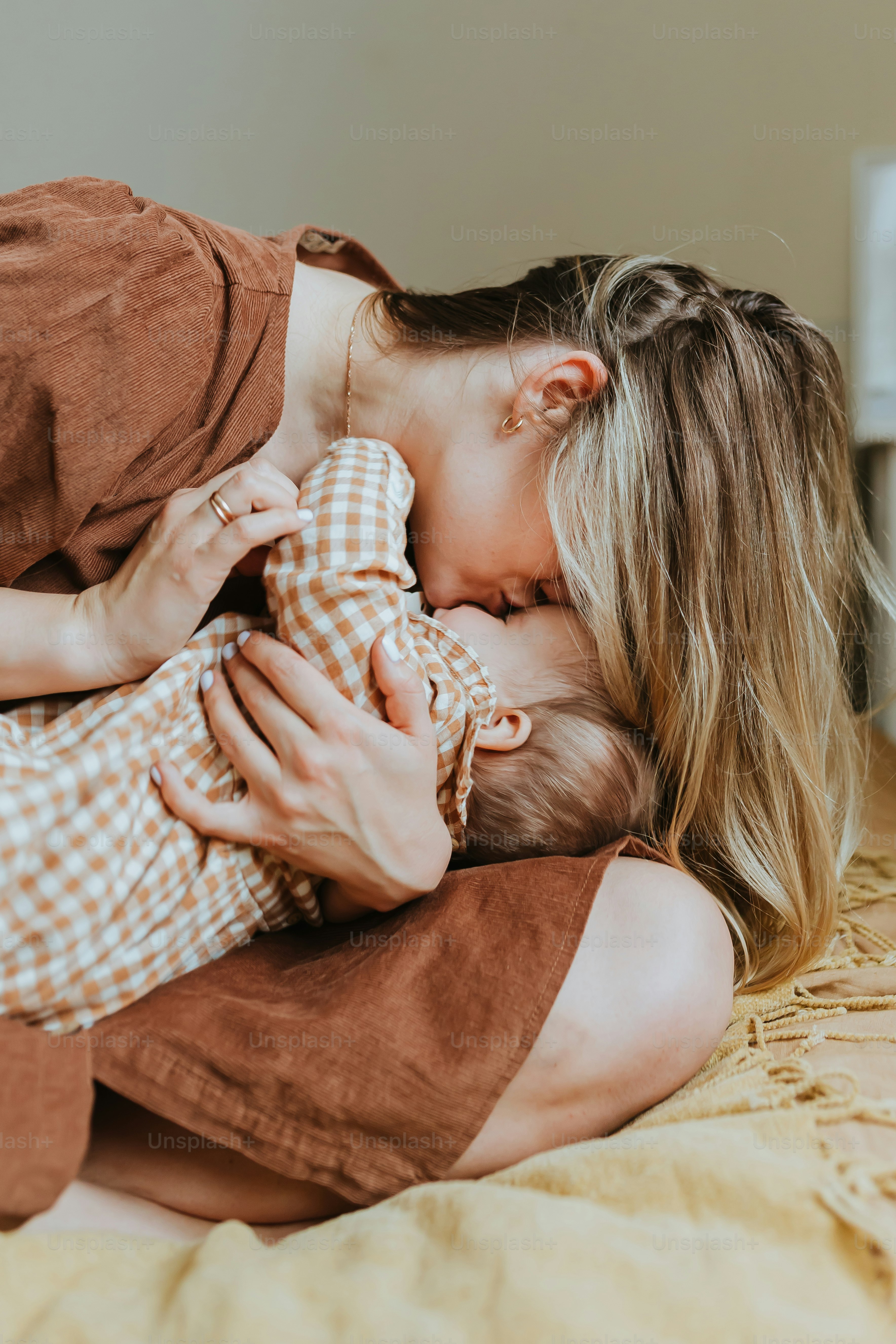 a woman holding a baby while laying on a bed