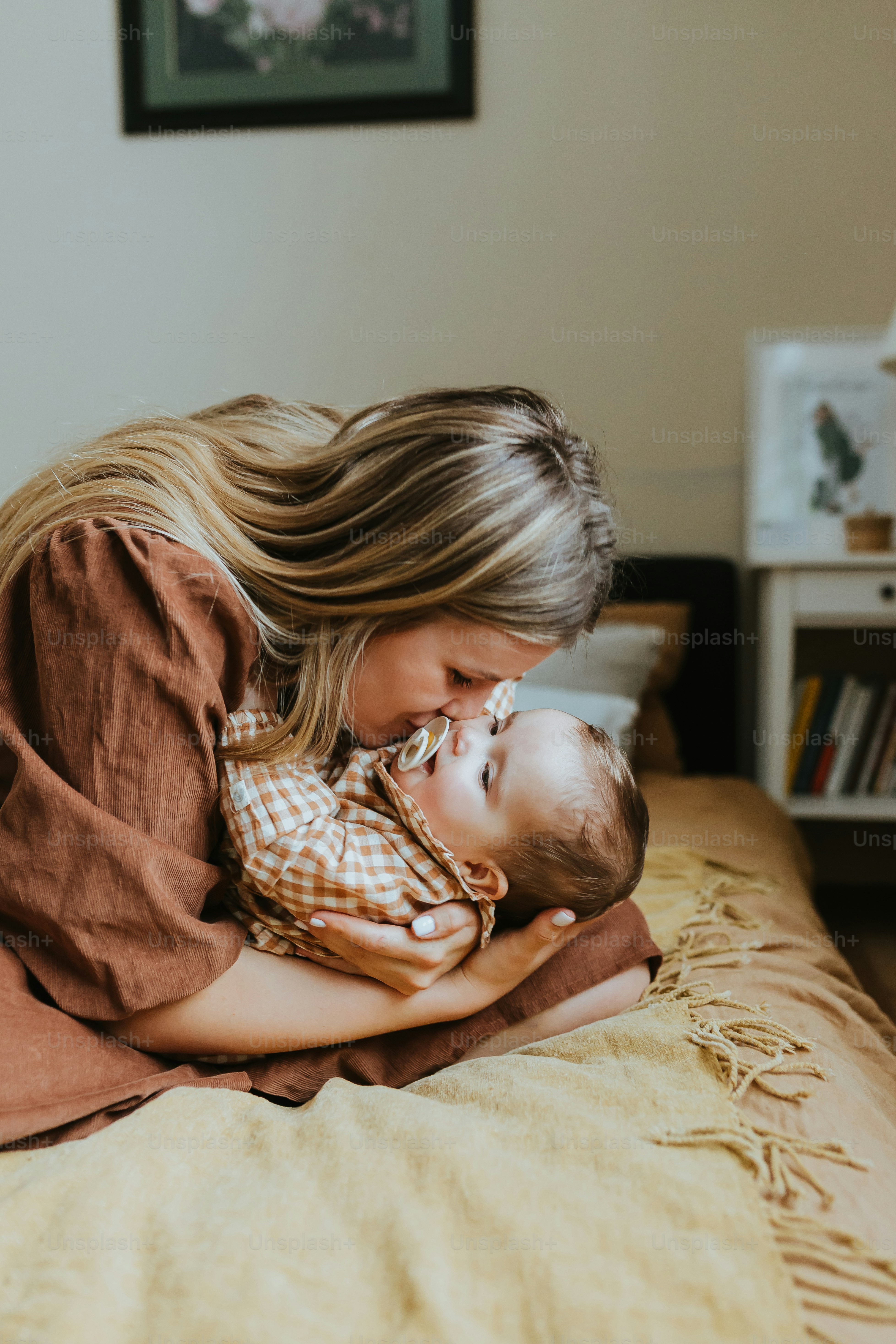 a woman holding a baby on top of a bed